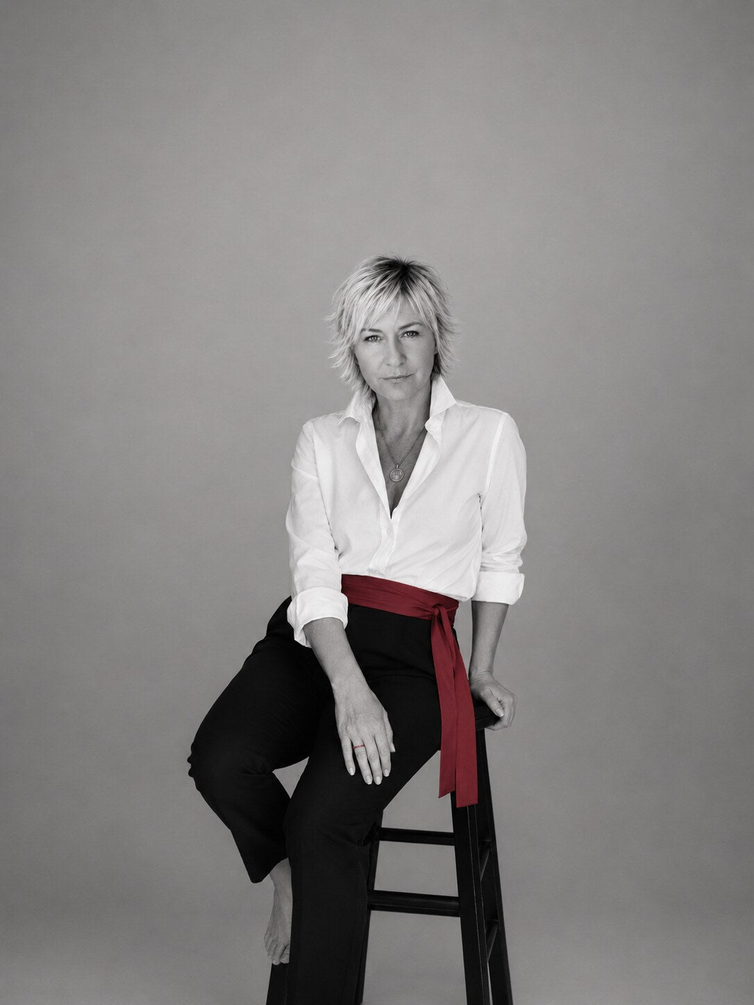 MenoEssentials founder seated in a white shirt with a red sash